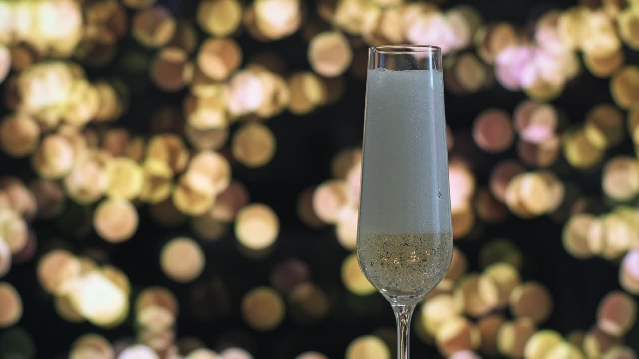A champagne flute being filled with sparkling wine, captured against a glowing golden bokeh background.