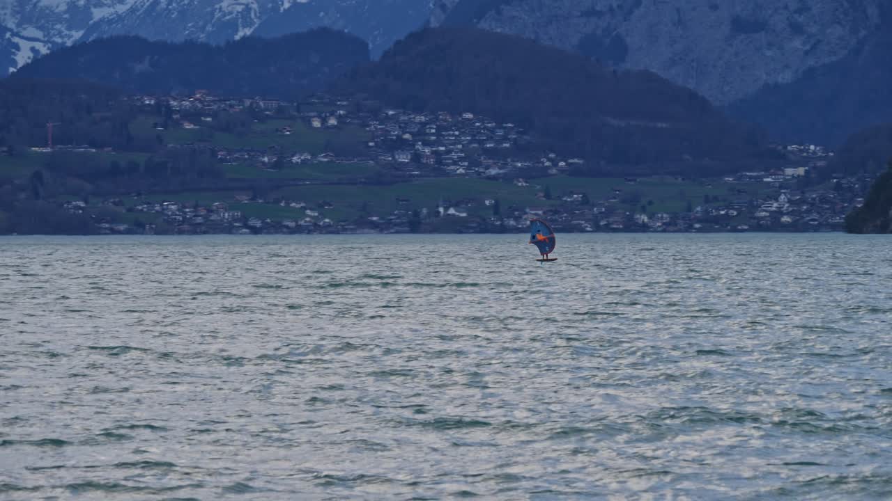 un hombre navega en un lago con una tabla de papel de aluminio y un ala