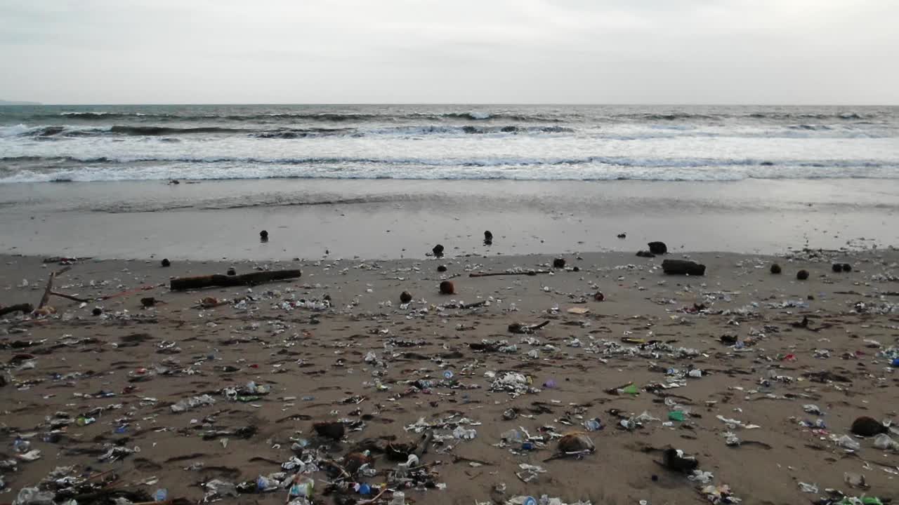 cámara moviéndose de lado en una playa muy contaminada, basura plástica lavándose de los océanos