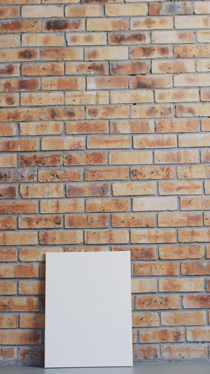 Vertical video of white canvas sign with copy space on floor against brick wall background