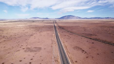 Drone-shot-flying-straight-over-a-desert-highway-and-railroad-track