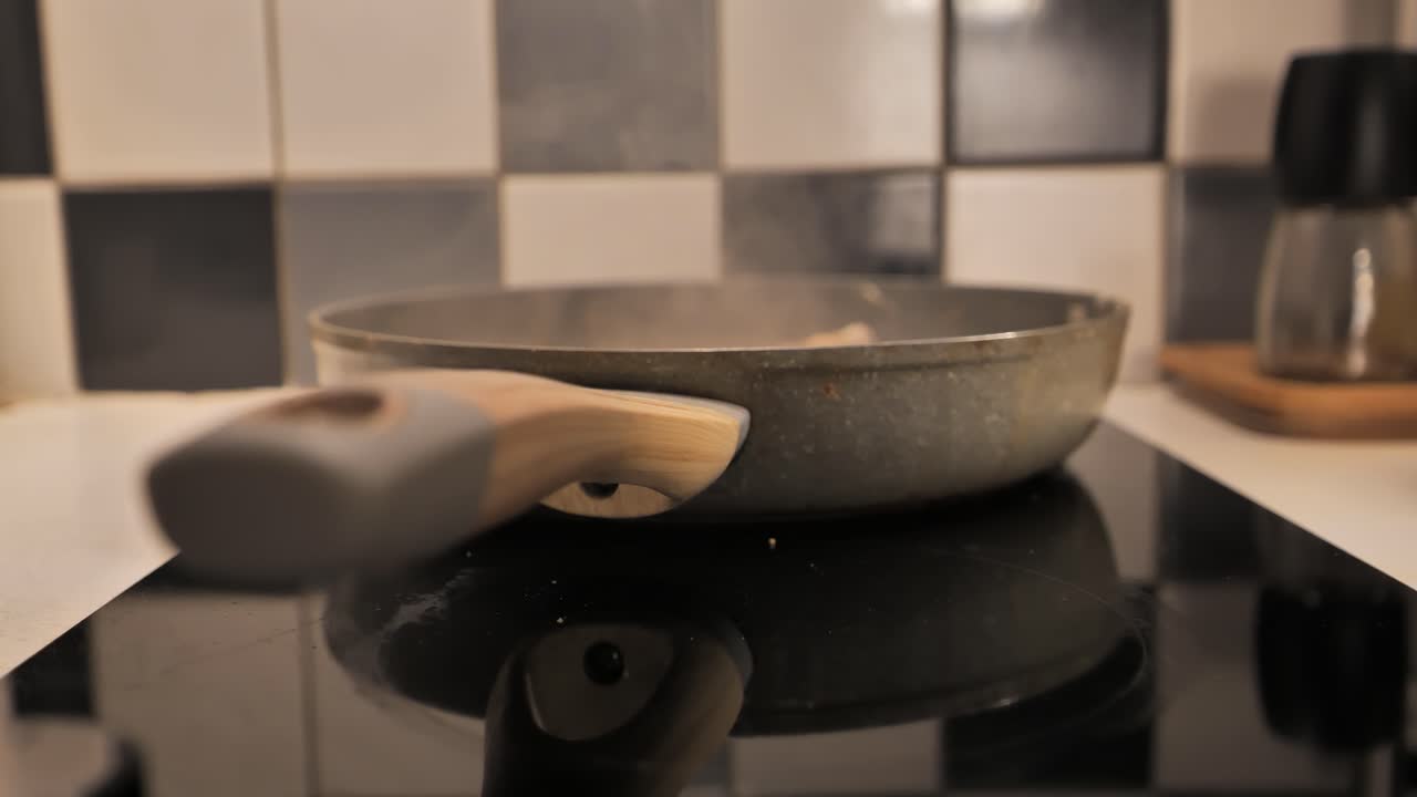 Focus shifts from frying pan to handle, capturing a cooking scene - 4K.