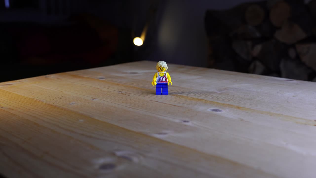 zoom en la mesa de madera sobre la que se encuentra una pequeña figura de juguete de plástico con una apariencia joven y un surfista en su parte superior