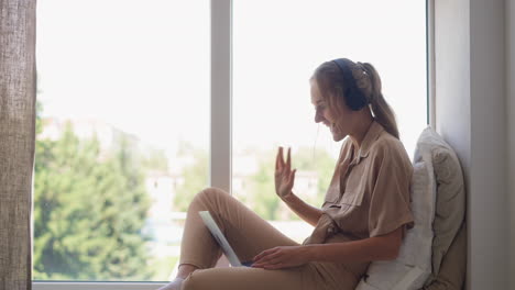 Mujer-Feliz-Se-Comunica-En-Videollamada-A-Través-De-Una-Computadora-Portátil-Agitando-La-Mano