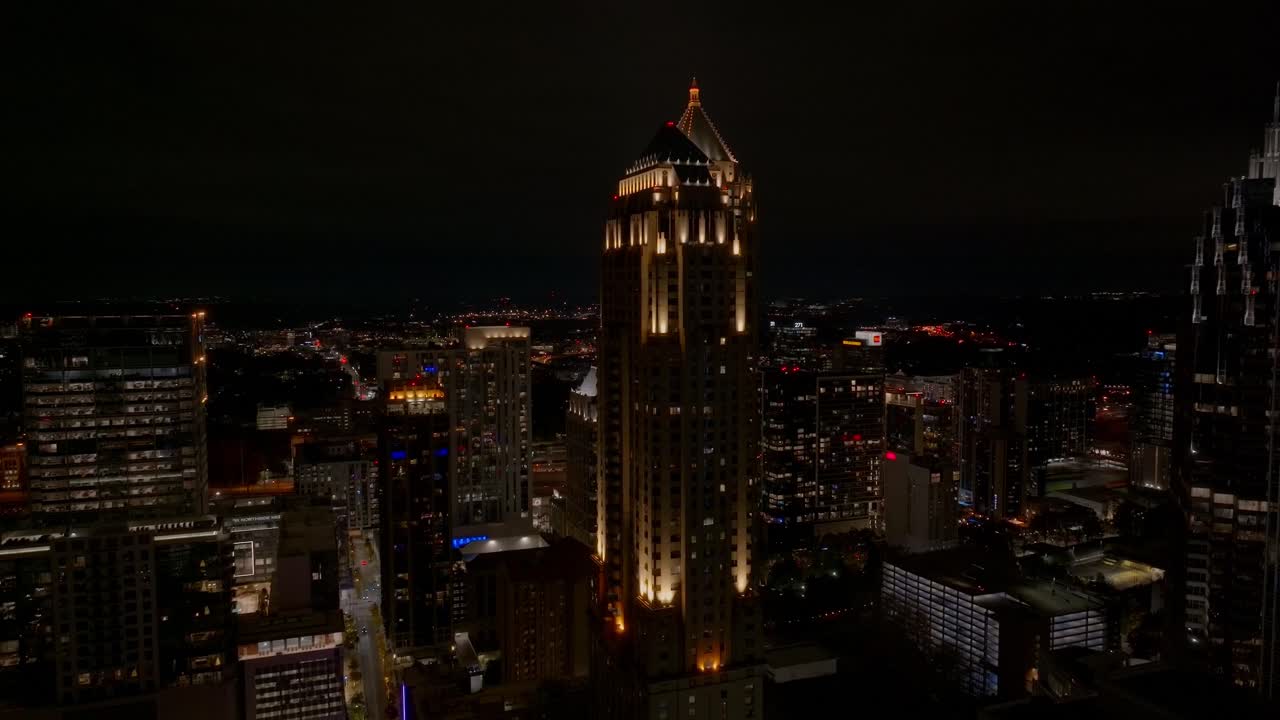 Drone shot of Atlanta Georgia skyscrapers and skyline commercial and residential buildings illuminated with night light