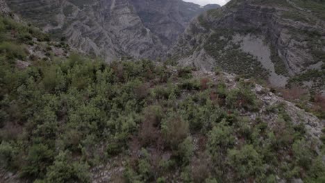 Video-Con-Drone-Del-Descubrimiento-Del-Avión-De-La-Carretera-Sh20-Entre-Las-Montañas-Y-El-Río-Cemi-En-Albania-A-La-Altura-De-Selce,-Cielo-Nublado-Y-Camino-Sinuoso