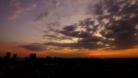 a wide angle shot of a sunset taken in a less populated part of bangkok. a cloudy afternoon and car lights are coming out after sunset