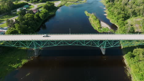 Aerial-View-Soars-High-Above-Large-Bridge-in-Maine's-Peaceful-Countryside