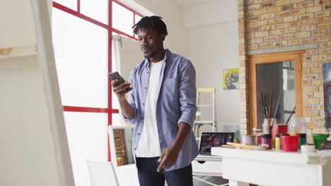 Afroamerikanischer-Männlicher-Künstler,-Der-Im-Kunststudio-Ein-Gemälde-Mit-Einem-Smartphone-Fotografiert