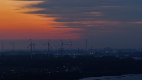 skyline of darkness and orange over operating rotterdam city wind farm