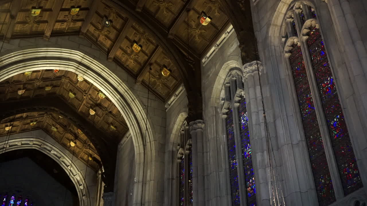 Vaulted cathedral ceiling with wooden panels, and stained glass gothic windows with tracery