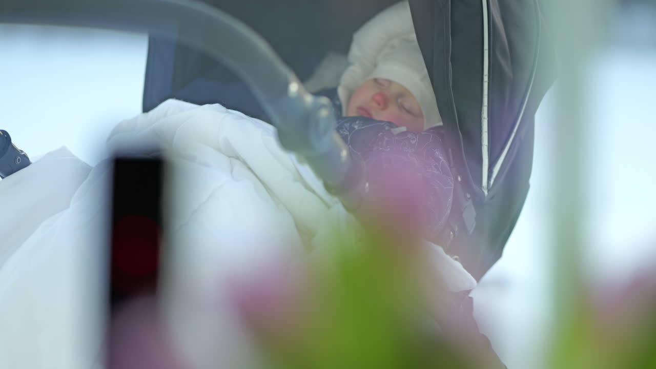 Baby sleeping in a winter stroller with a baby alarm, peaceful and cozy outdoors