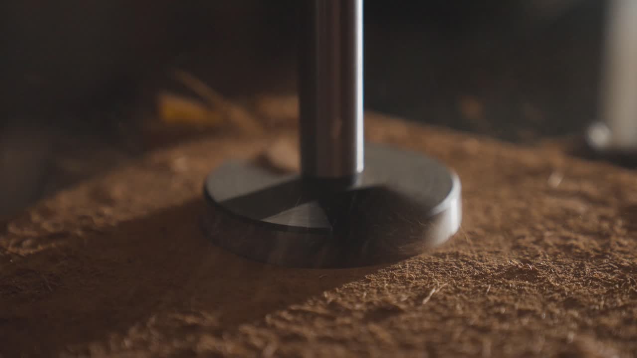 Industrial drill bit creating hole in wooden board, sawdust flying, slow motion