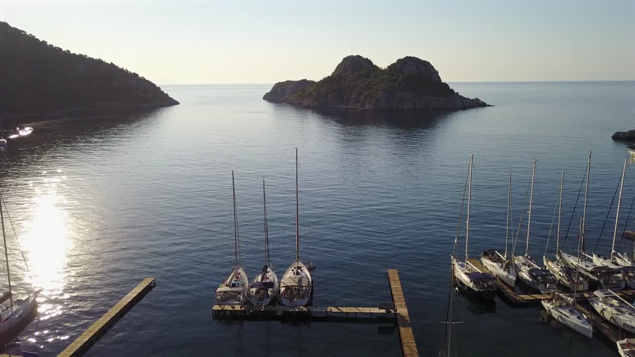 Veduta aerea della baia di Cifltik, riprese di barche a vela con la poppa verso i moli di un ristorante e la prua verso il mare aperto e le isole