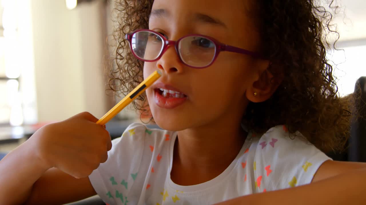 African american schoolgirl studying at desk in classroom at school 4k