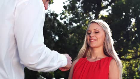 hombre sonriente ofreciendo anillo de compromiso mientras le propone a la mujer