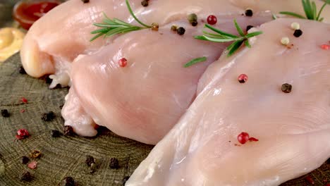 fresh raw chicken breast fillets sprinkled with peppercorns and rosemary rotates slowly.