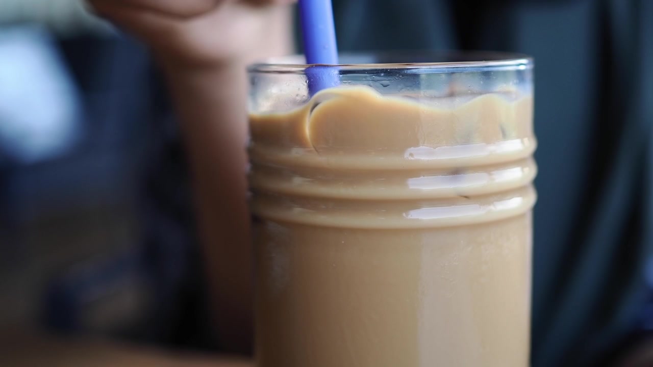 Primo piano di caffè freddo mescolato con una cannuccia blu