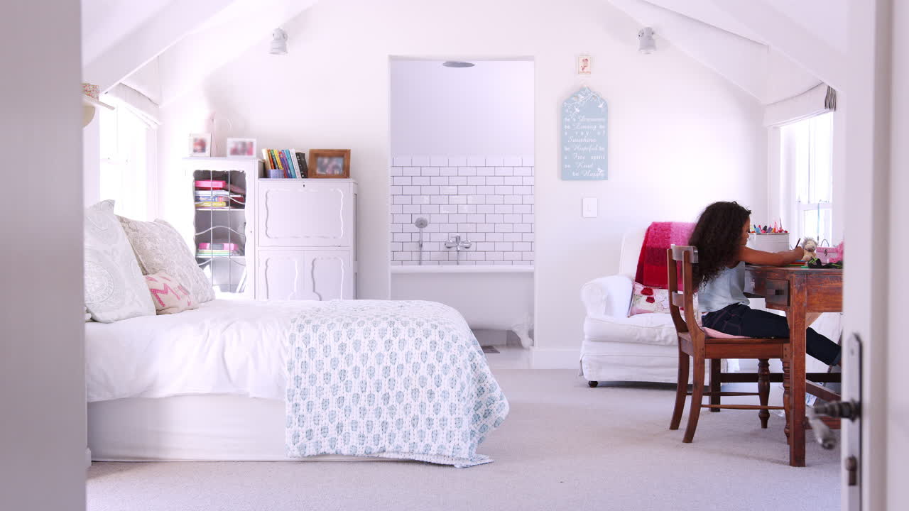 책상에 앉아서 방에서 숙제를 하고 있는 젊은 흑인 소녀