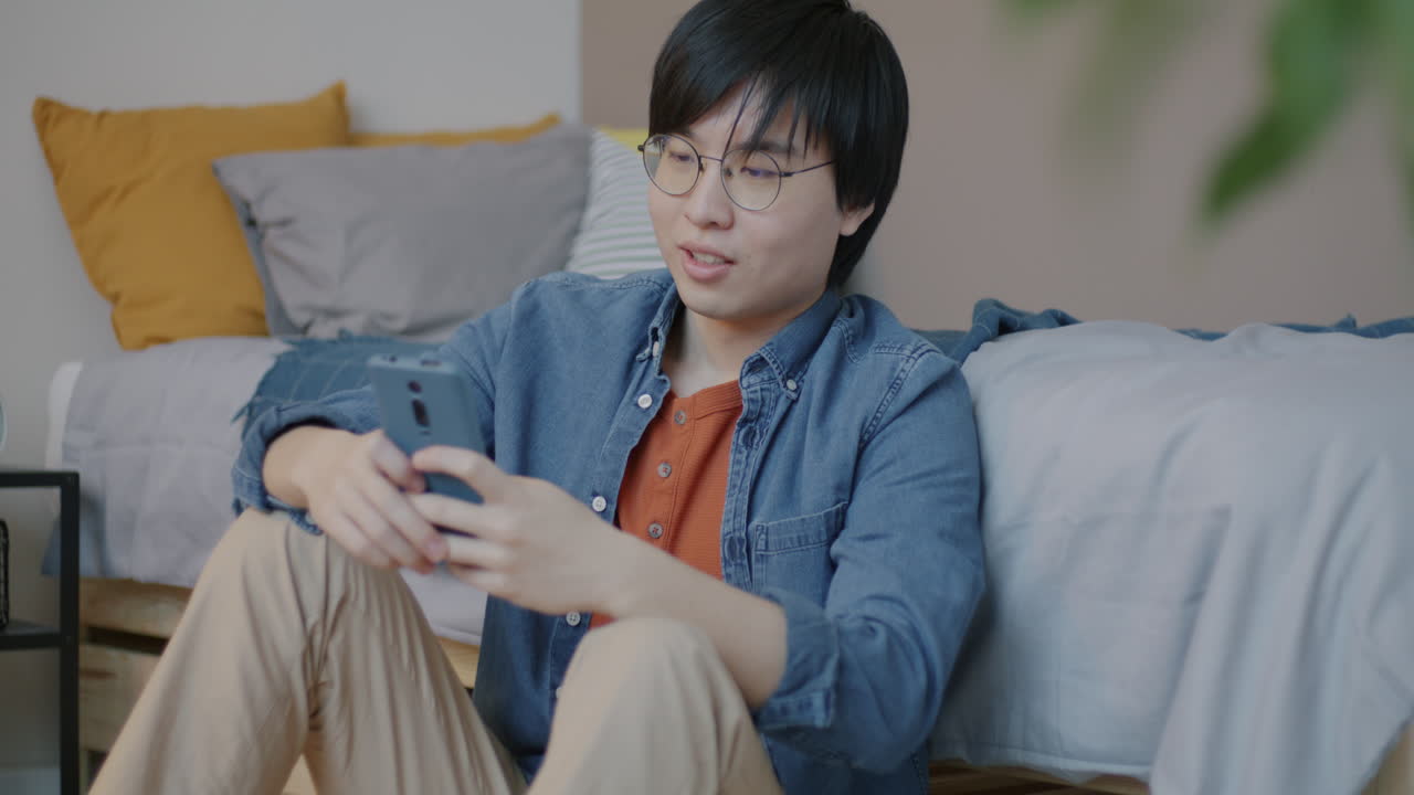 Young Man Using Smartphone in Bedroom