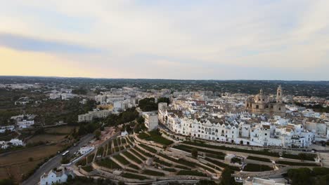 Aerial-panoramic-view-over-Locorotondo-village-houses-and-terrace-vineyard,-traditional-italian-hilltop-town,-at-sunset