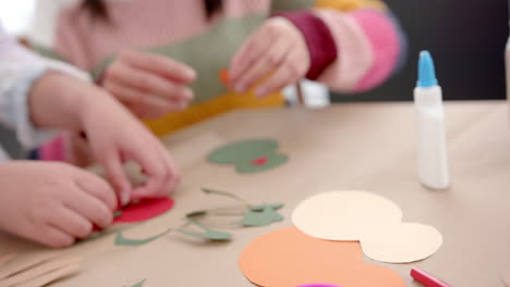 Happy-biracial-mother-and-daughter-sticking-colourful-cutouts-in-sunny-living-room