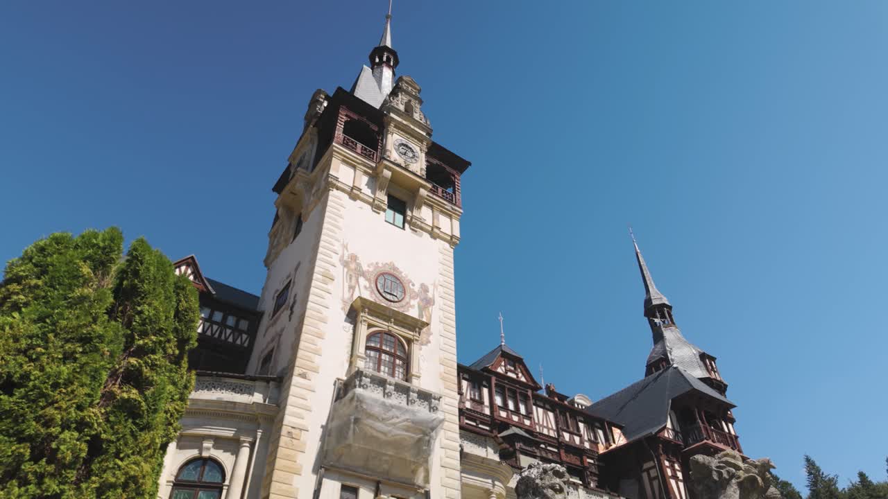 Peles Castle in Sinaia, Romania, with a statue prominently positioned in the foreground, highlighting the castle’s ornate architecture