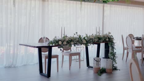 beautifully decorated wedding table with white flowers and greenery, elegant chairs, and candles