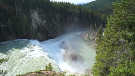 large waterfall in the mountains creating mist as it hits the large mountainous rocks below