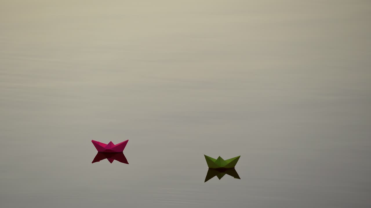 Beautiful paper boats floating. Two colorful origami ships swimming with their reflection in water. Freedom and hope concept.