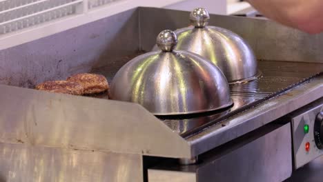 la carne de res se cocina en una sartén caliente. comida callejera, el chef lanza hamburguesas con una espátula.