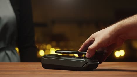 pagar con un primer plano de teléfono inteligente. compras sin efectivo en un restaurante o cafetería. concepto de pago sin contacto y sin contacto. tecnología nfc y terminal bancario.