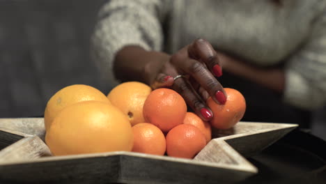 black woman picking mandarin, oranges from a bowl