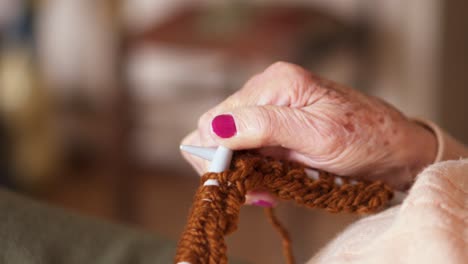 los dedos arrugados de la abuela mientras tejía con lana marrón