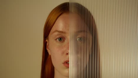 mulher com cabelo vermelho atrás de um painel transparente