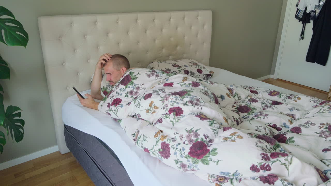 hombre dormido se despierta después de la alarma en su teléfono inteligente