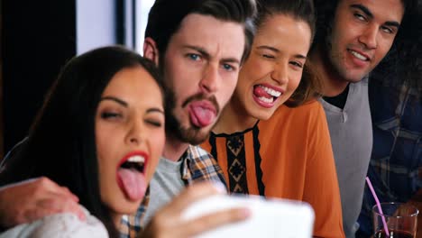 amigos haciendo caras divertidas y tomando una selfie en el teléfono móvil