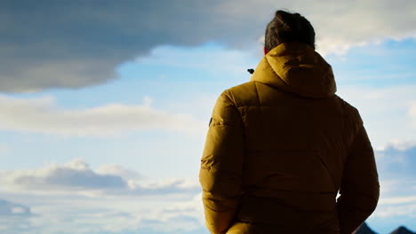 traveler stands alone at the edge of a towering mountain range