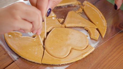 mom with kid scratch out heart shape from dalgona sugar candy like in squid game - close-up