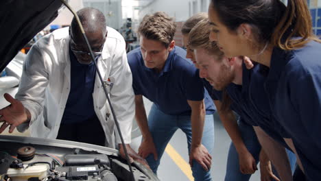 tutor explaining how engine works to group of apprentices