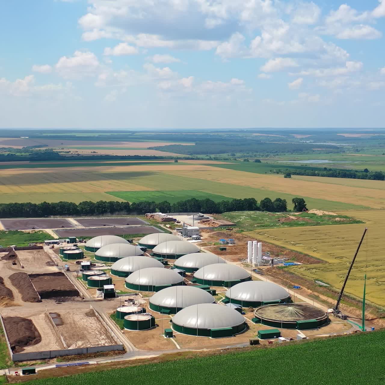 Industry on field under blue sky. Innovative biogas plant in agricultural land. Biomass production in special reservoirs. Aerial view