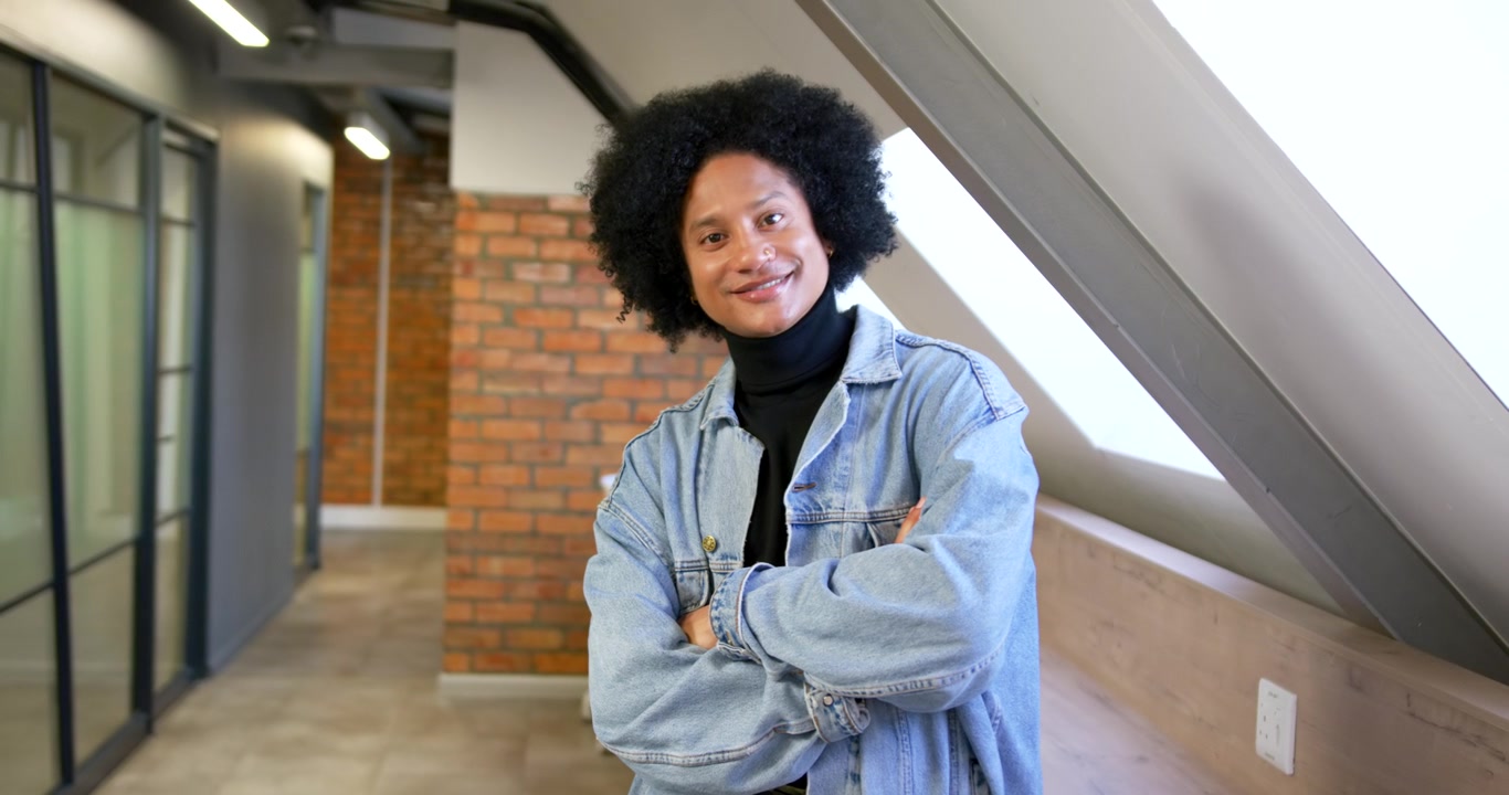 African American man in corridor shifting gaze, skylight drawing gaze, leaning on ledge and smiling