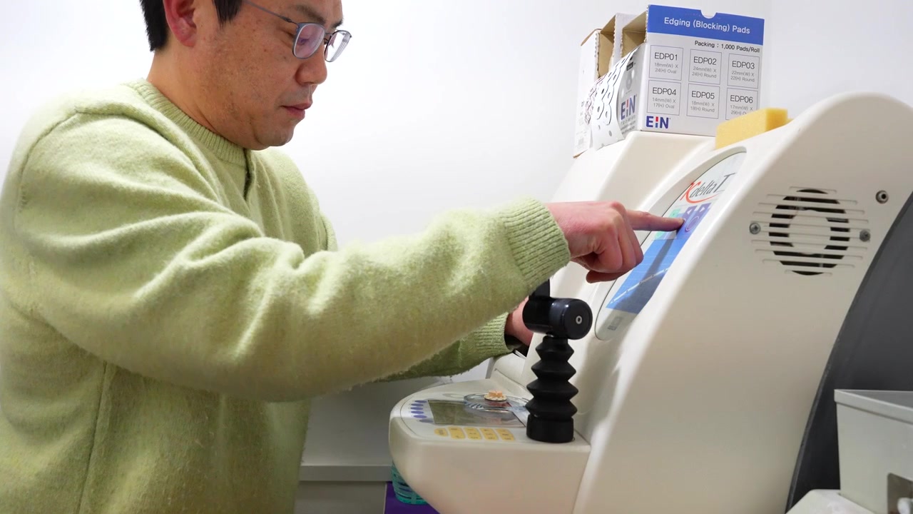 最新の機械を使用して光学研究所で眼鏡を製作しているアジア人男性