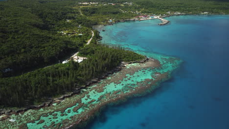 stijgende luchtfoto die het verbazingwekkende coral bay-strand en de tadine-werf onthult, op het eiland maré, nieuw-caledonië