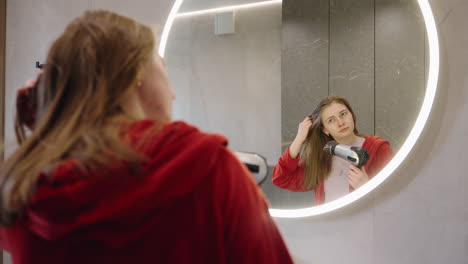mujer secándose el cabello en el baño