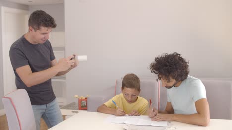 focused boy doing school home task with help of two dads