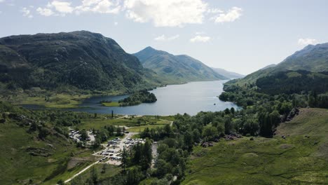 Luftaufnahme-über-Die-Stadt-Glenfinnan-In-Der-Schottischen-Landschaft-Mit-Loch-Shiel-Im-Hintergrund