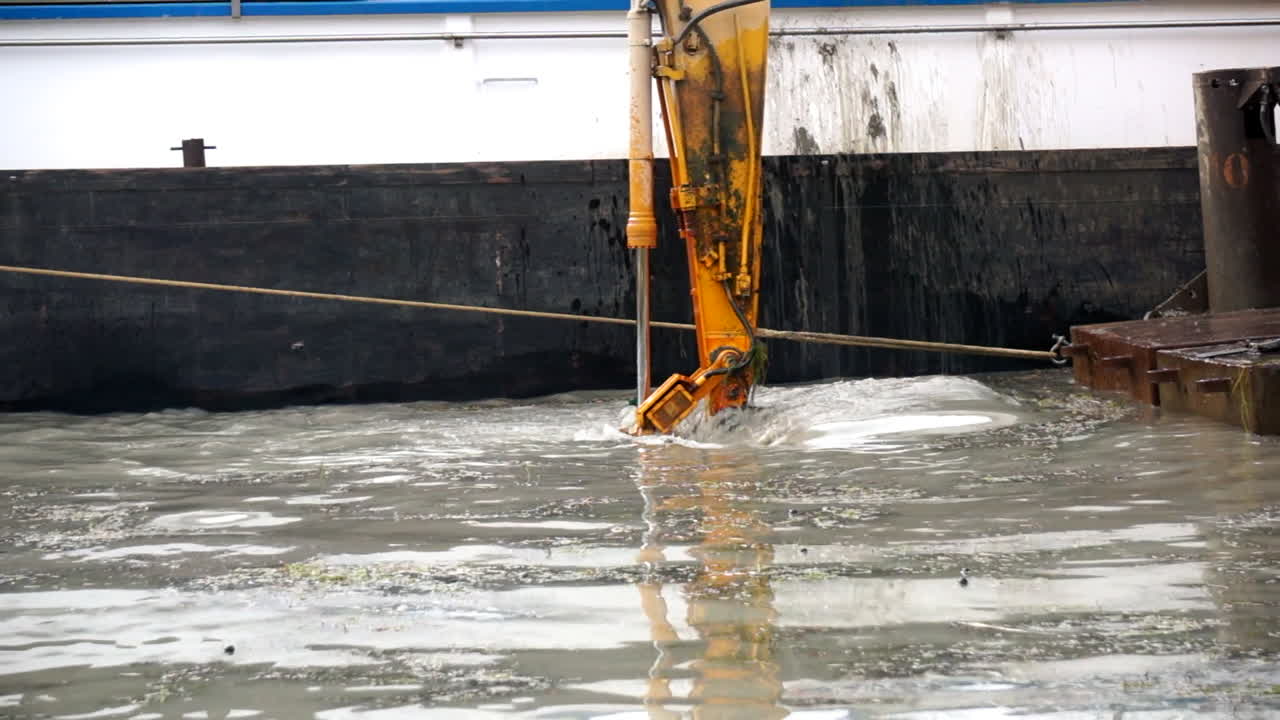 toma de la pala de una excavadora en un pontón junto a un barco, profundizando un canal slomo