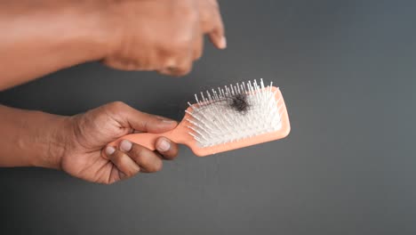 woman's hand holding a hairbrush with hair falling out