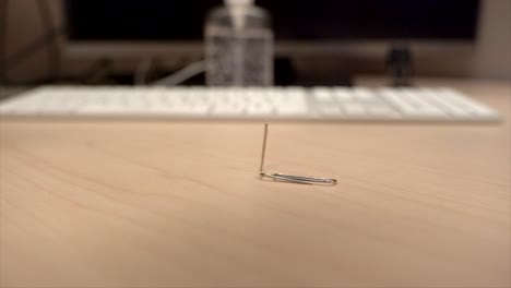 a hand full of paper clips slowly dropping onto an office desk in super slow motion a little bit at a time